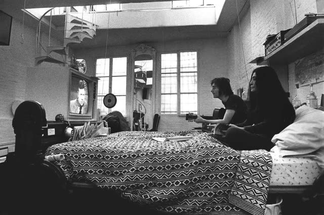 John Lennon and Yoko Ono on the bed in the reconstructed Greenwich Village apartment set from 'One to One: John & Yoko'